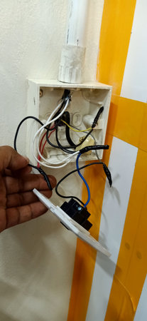 Close up of electrician's hand holding a wire on the wallの写真素材