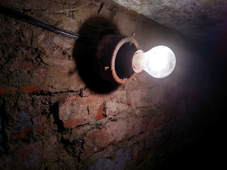 bright light bulb on a brick wall in the basement of the old