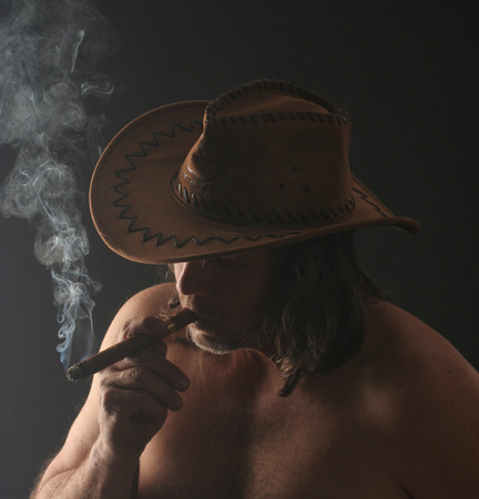 attractive man with long hair and a hat smoking a cigarの写真素材