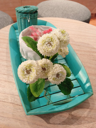 Beautiful White artificial flower decoration on the coffee table with green tray