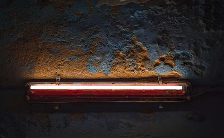 Glowing fluorescent lamp in an old rusty red shade. Highlights a beautifully crumbling blue concrete wall. The atmosphere of horror.の写真素材