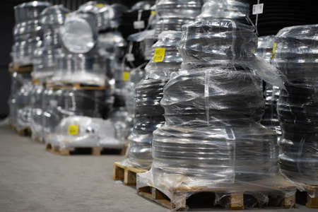 Black plastic pipes wrapped in foil on a pallet in a warehouse. Pipe packaging ready for transportation.の写真素材