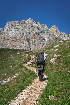 A tourist with a backpack walks along a path in the mountains. Hiking in the mountains.の写真素材