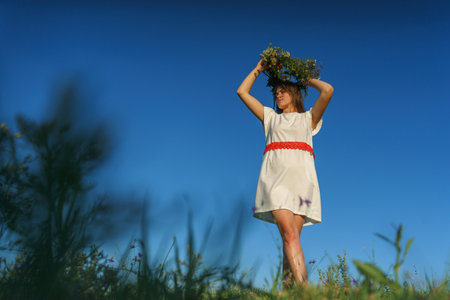 Portrait of a girl in a white dress, Slavic appearance with a wreath of wild flowers on her head.の写真素材