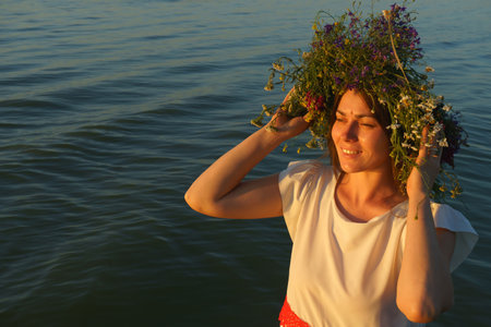 Portrait of a girl in a white dress, Slavic appearance with a wreath of wild flowers on her headの写真素材