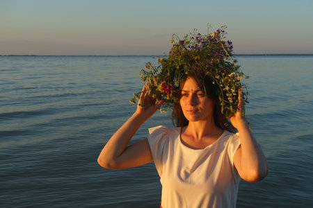 Portrait of a girl in a white dress, Slavic appearance with a wreath of wild flowers on her headの写真素材
