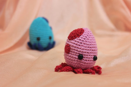 Cute couple of octopuses playing together. The colors are red and blue, made with cotton yarn, using the crochet technique. Amigurumi Crochet.の写真素材