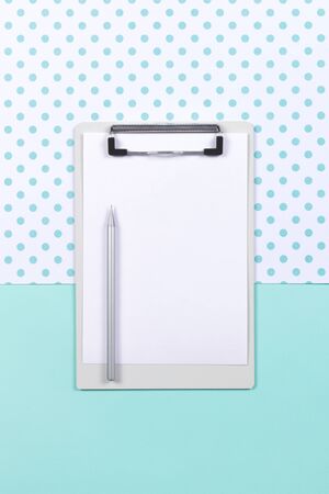 Clipboard with sheet of blank paper and silver pencil on mint polka dot background. Flat lat, copy space. Mockup with white card.の写真素材