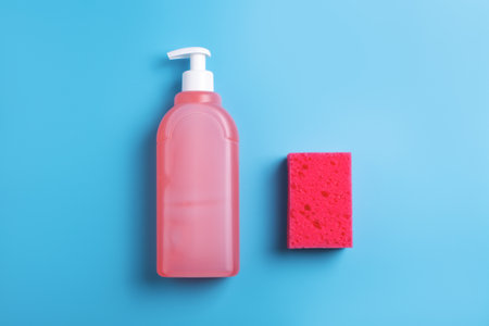 Red dishwashing soap and sponge on blue background. Top view.の写真素材