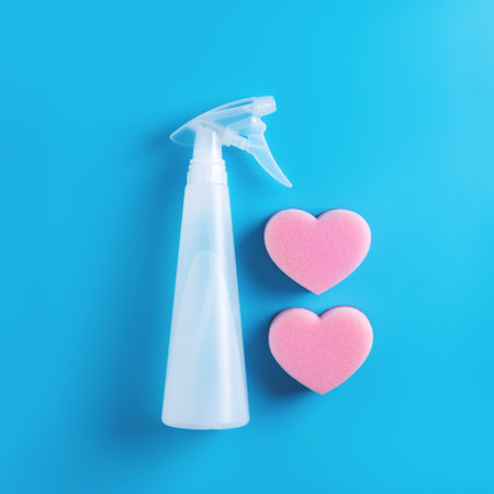 Cleaning spray and two pink heart shaped sponges on blue background. Top view.の写真素材