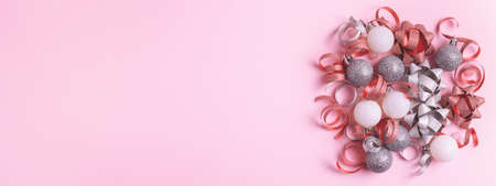 Christmas banner with festive decorations on pastel pink background. Sparkly baubles, ribbons and bows. Top view, copy space.の写真素材