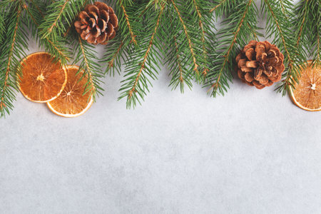 Winter natural decor on grey background. Spruce branch, pine cones and dry orange. Flat lay, top view, copy space.の写真素材