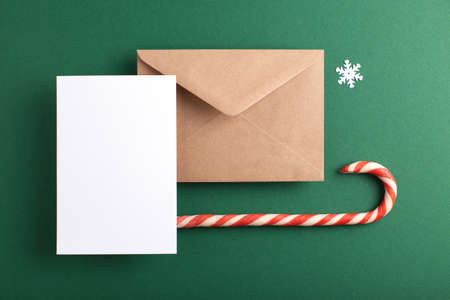 Blank card, kraft envelope and Christmas decoration on green background. Holiday and Seasons greetings.の写真素材