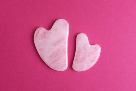 Acupressure pink transparent gua sha massagers of different size isolated on bright pink background. Top view.の写真素材