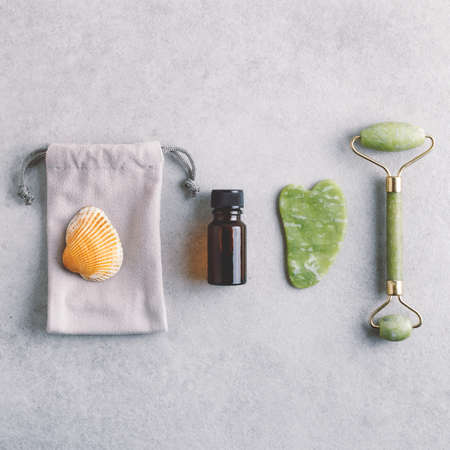 Square cosmetology flat lay with natural face massaging tools. Face oil and gua sha jade stone massagers. Self care and skin care concept.の写真素材