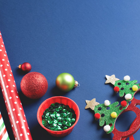 Close-up of green glitter, New Years gift wrapping paper, sparkling festive Christmas decor, baubles on a blue background. Holiday elegance in square composition with copy space.の写真素材