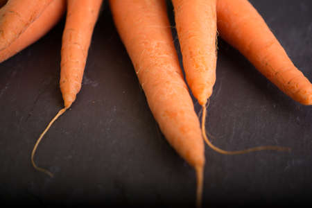 Ripe fresh carrots with greens on a black background.の写真素材