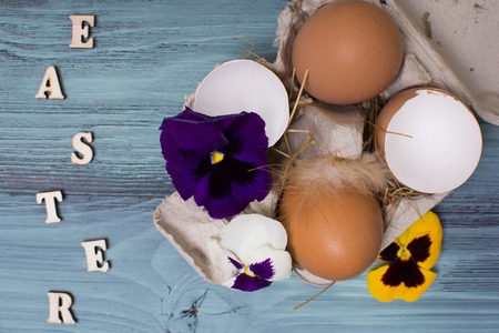 Easter eggs and tulips over blue wooden table. Top view. Wooden letters.の写真素材