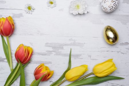 Easter eggs and tulips over wooden background.
