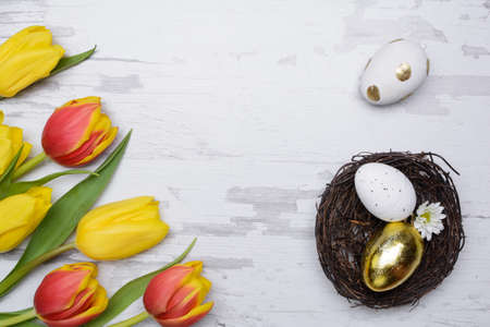 Easter eggs and tulips over wooden background.