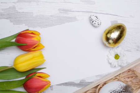Easter eggs and tulips over wooden background.