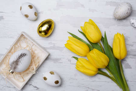 Easter eggs and tulips over wooden background.