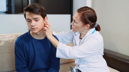 Woman doctor puts a hearing aid on a young guy.の写真素材