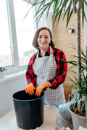 Florist woman portrait with large black flowerpot. Preparing for plant transplantation.の写真素材