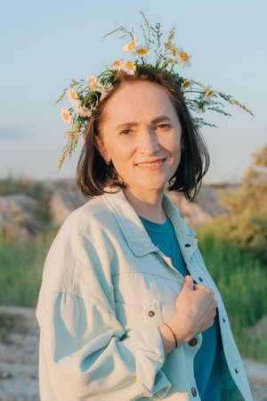 Woman with a beautiful wreath of summer wildflowers on her head. Chamomile wreath. Summer time.の写真素材