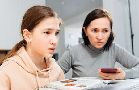 A happy family. Girl and mother are doing homework while sitting at a laptop in the room. Mom...
