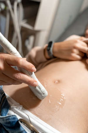 Ultrasound diagnostics of the stomach on the abdominal cavity of a girl in the clinic, close-up. The...