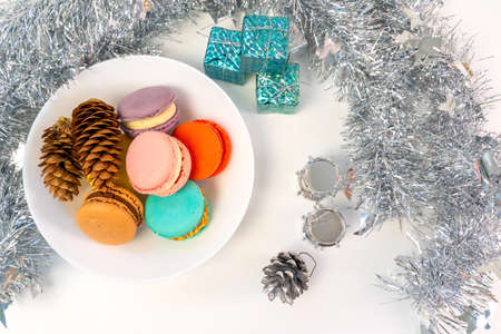 Multicolored French cookies in a white plate on a tinsel background.の写真素材