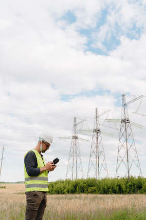 An engineer examines a high-voltage tower with a drone.の写真素材