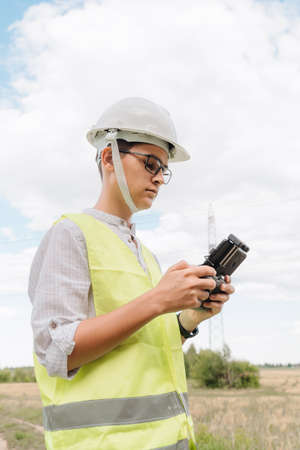 A young Engineer examines the high-voltage tower with a drone.の写真素材