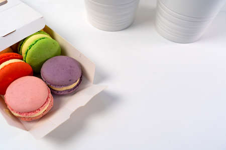 Opened Box of Macarons on a white table against the backdrop of a decorative flower in a pot.の写真素材