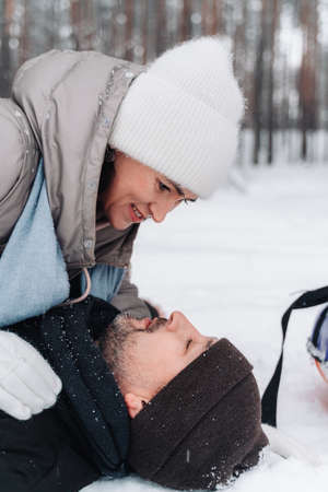 A married couple is having fun in the forest at the weekend. A man and a woman lie on the snow. Married couple having fun. Christmas Holidays.の写真素材