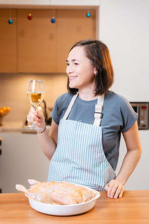 Smiling woman with a glass of white wine in the kitchen.の写真素材
