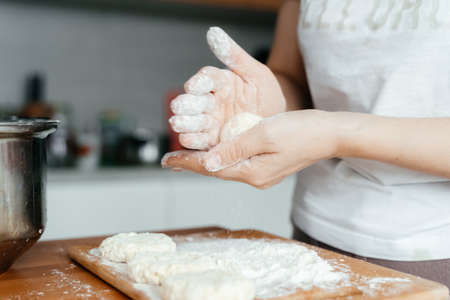 Womens hands mold delicious cheesecakes. Womens hands with flour close-up.の写真素材