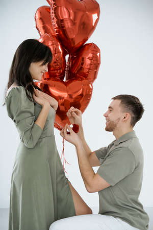 Man makes present to his lovely sweetheart girl. Lovers valentine day. The guy, on his knees, gives his girlfriend a piece of jewelry. Wedding ring. Happy smile girl.の写真素材