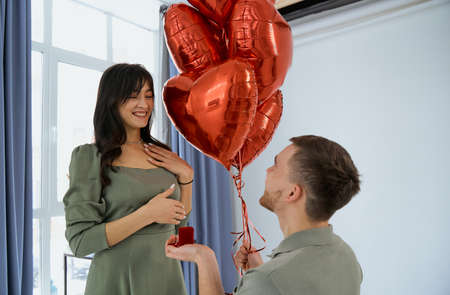 Man makes present to his lovely sweetheart girl. Lovers valentine day. The guy gives his girlfriend a piece of jewelry. Wedding ring. Happy smile girl.の写真素材