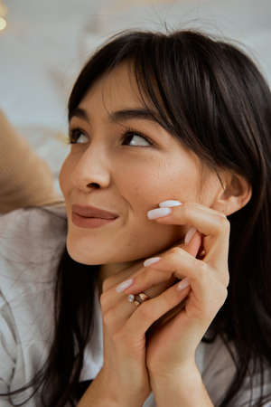 Portrait of a young beautiful woman. The girl lies on her stomach in bed. Girls hands near her face.の写真素材