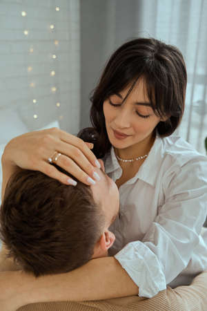 The girl hugs the guy. Husband and wife are sitting on the bed. The concept of love, relationships.の写真素材
