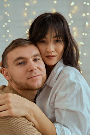 A girl and a guy sit on the bed hugging each other. Portrait of a young couple. The concept of love, relationships.の写真素材