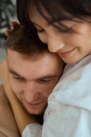 A girl and a guy sit on the bed hugging each other. Portrait of a young couple. The concept of love, relationships.の写真素材