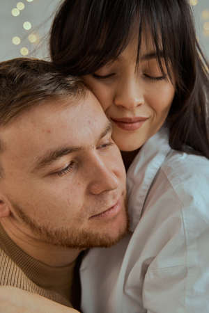 A girl and a guy sit on the bed hugging each other. Portrait of a young couple. The concept of love, relationships.の写真素材
