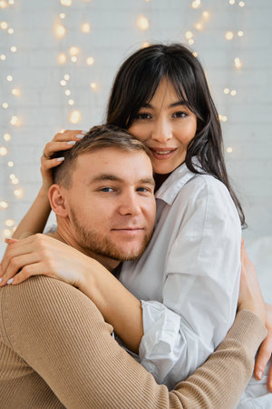 A girl and a guy sit on the bed hugging each other. Portrait of a young couple. The concept of love, relationships.の写真素材