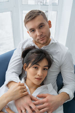 Happy dreamy young caucasian couple rest cuddle on couch in room thinking or visualizing, smiling...