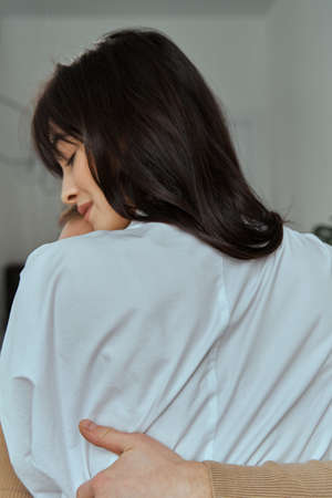A girl and a guy sit on the bed hugging each other. Portrait of a young couple. The concept of love, relationships.の写真素材