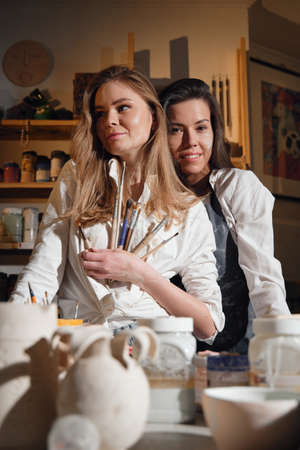 Two beautiful girls in a pottery workshop in a cozy studio, love and relationship.の写真素材