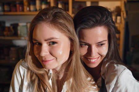 Two beautiful girls in a pottery workshop in a cozy studio, love and relationship.の写真素材